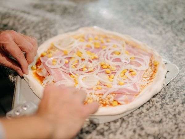 Frisch belegte Pizza mit ausgewählten Zutaten in der Küche von Giuseppe